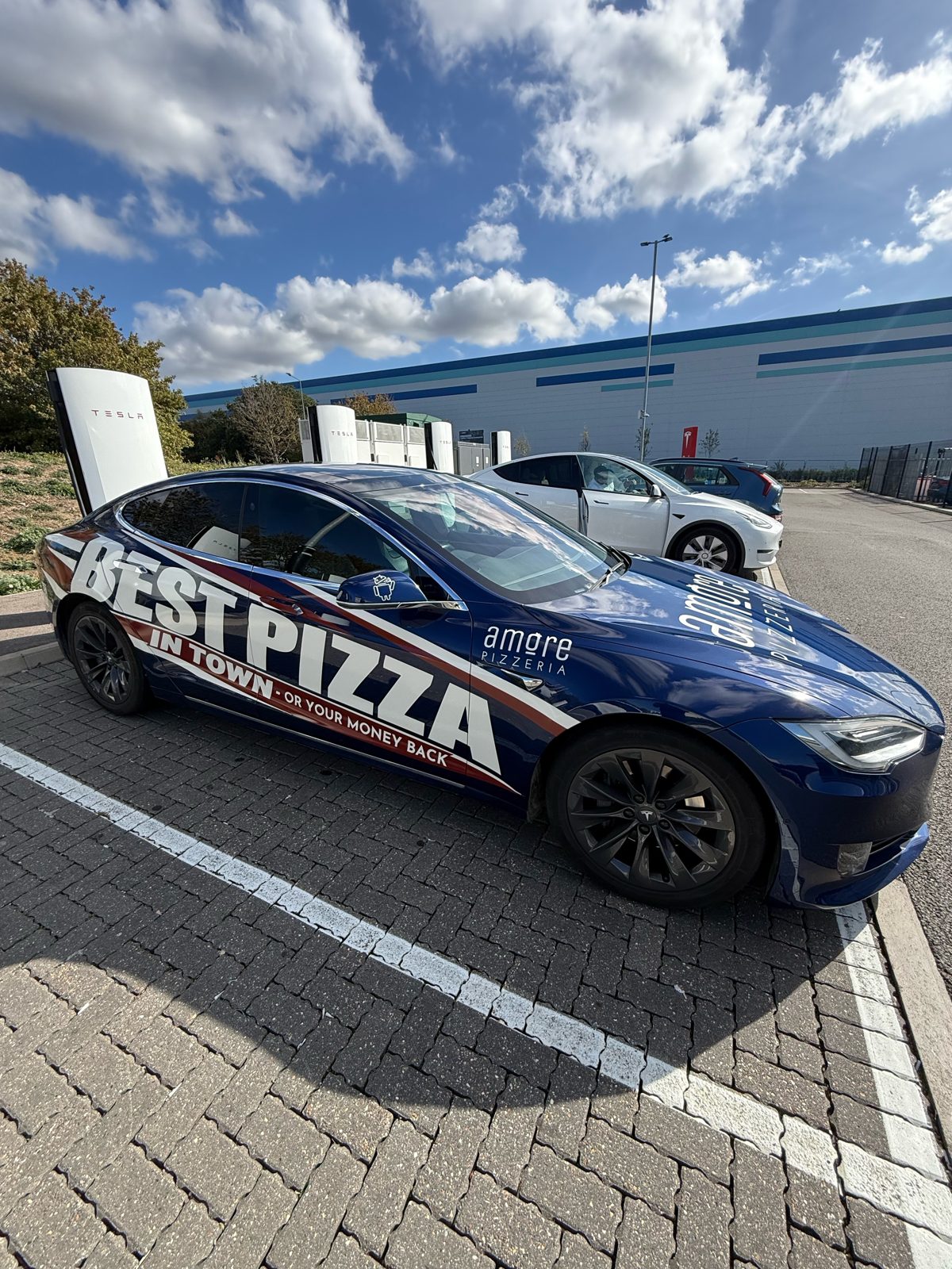 Amore Pizzeria blue car with Best Pizza in Town wrap, rear view