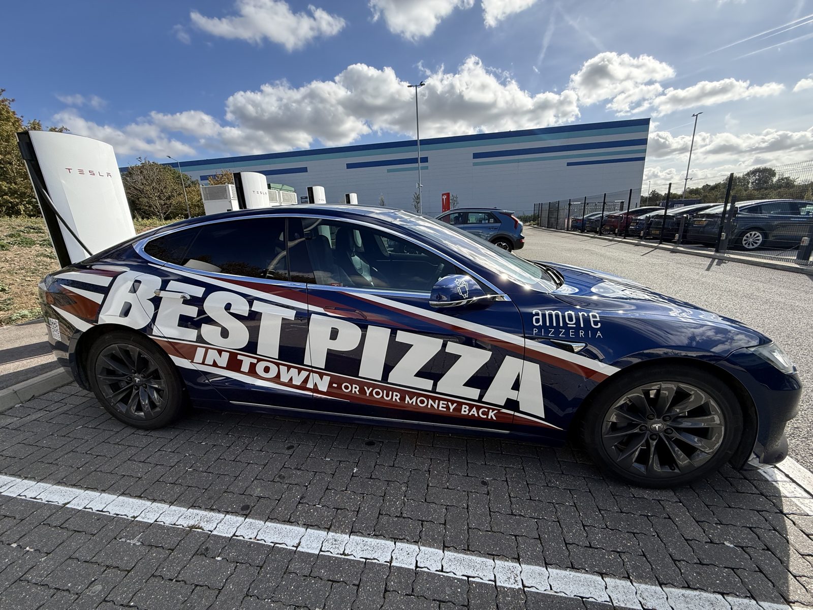 Amore Pizzeria blue car with Best Pizza in Town wrap, parked outside