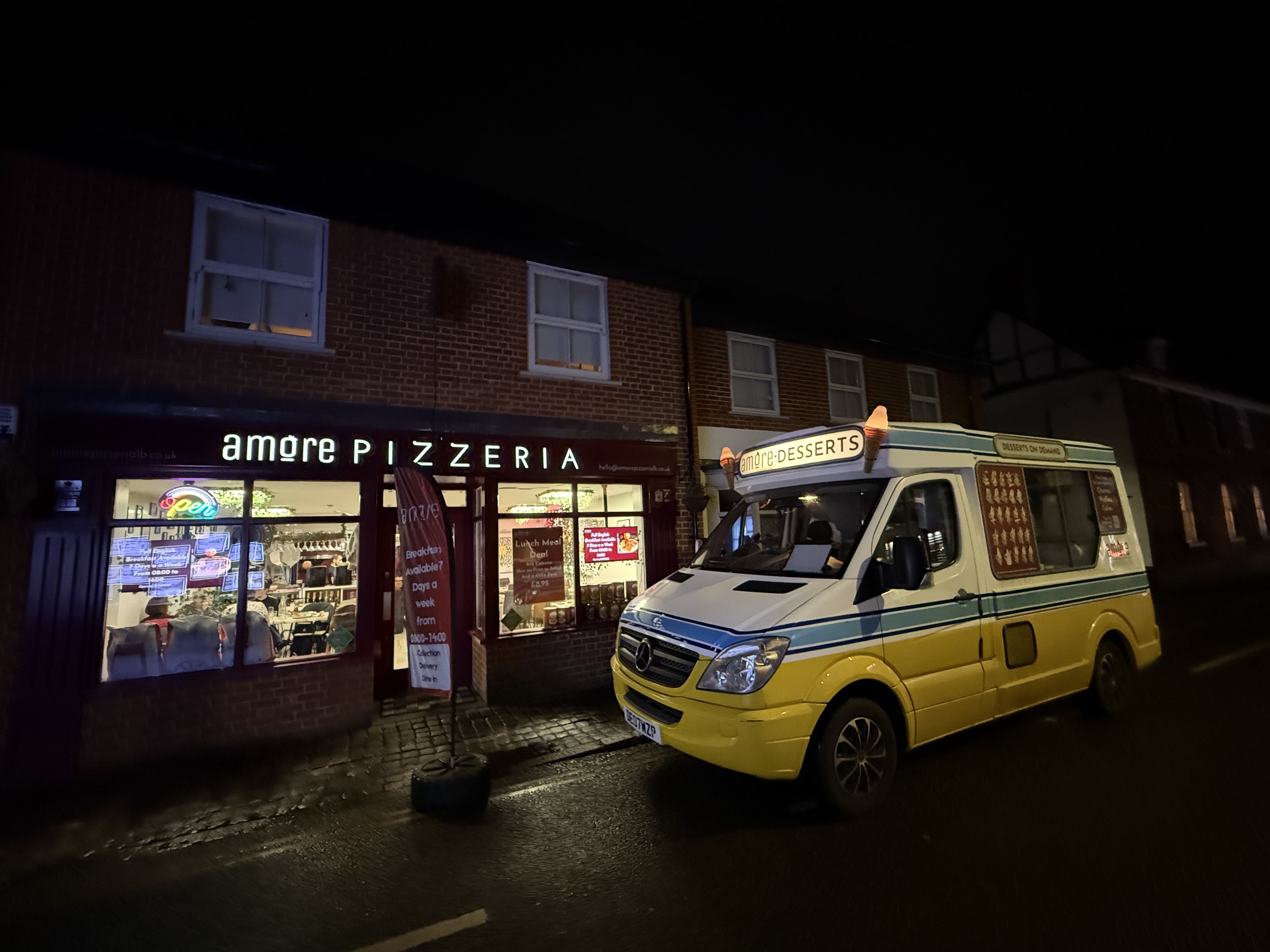 Amore Pizzeria storefront at night with the Amore Desserts ice cream van