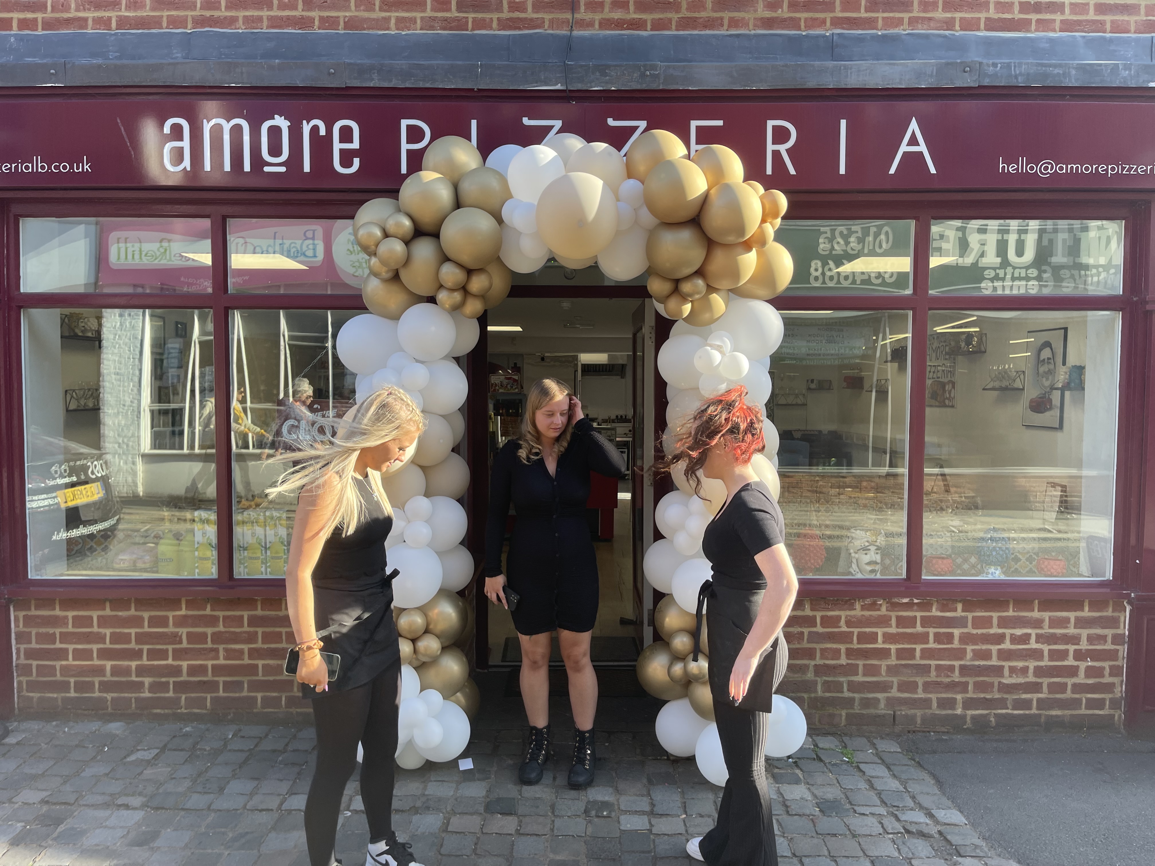 Amore Pizzeria team celebrating outside the restaurant with balloon decorations